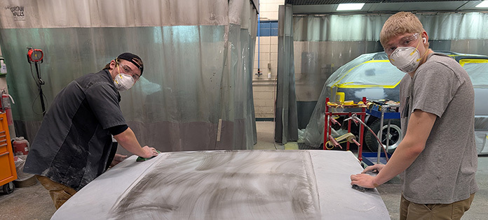 Image of Collision Repair student sanding the hood of a car.